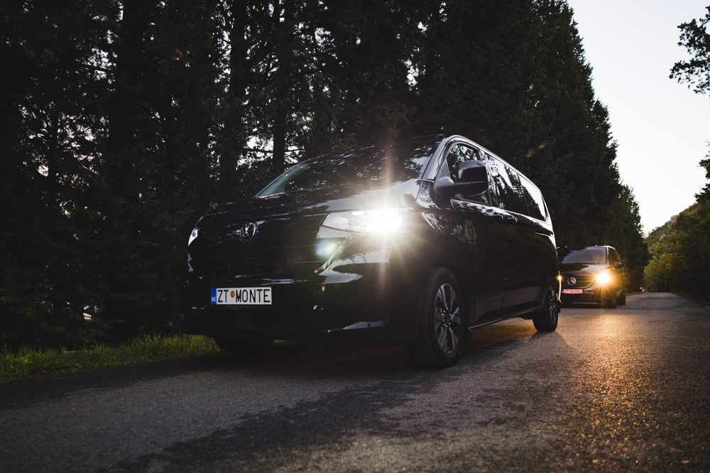A black Volkswagen Multivan of Monte Zeta limo service on a road in Montenegro at dusk