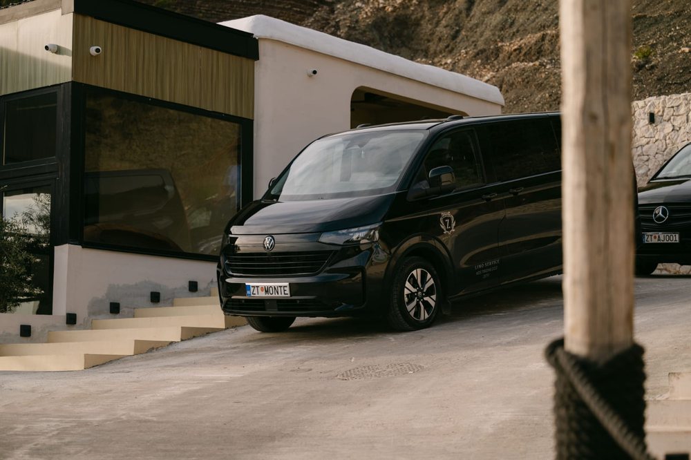 Black Volkswagen Caravelle with the Monte Zeta crest parked above the Adriatic sea