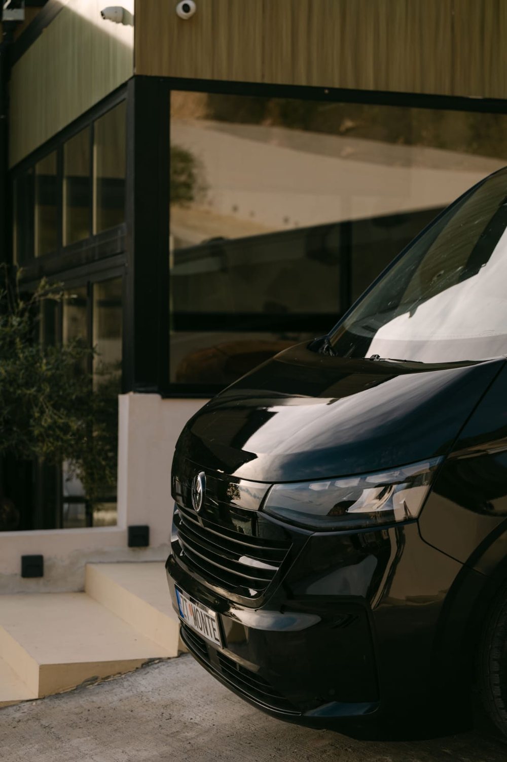 Black Volkswagen van in warm evening light in front of a modern villa